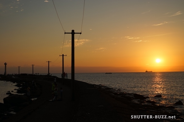 沈む夕日、海に続く電柱
