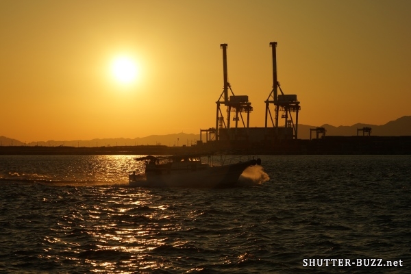 夕暮れに染まる2機の“麒麟”と、波しぶきを上げて突き進む漁船